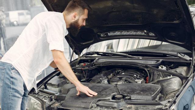 Un hombre revisa el motor de su coche.