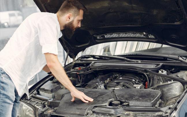 Un hombre revisa el motor de su coche.