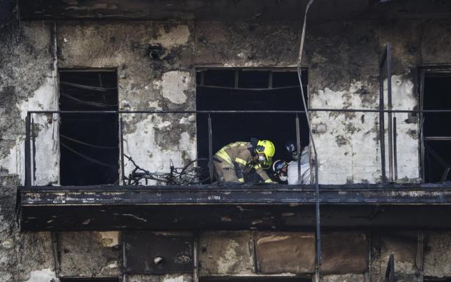 Un bombero y dos agentes de la Policía Científica inspeccionan un cuerpo en un balón del edificio incendiado. / Miguel ?ngel Polo Un bombero y dos agentes de la Policía Científica inspeccionan un cuerpo en un balón del edificio incendiado.