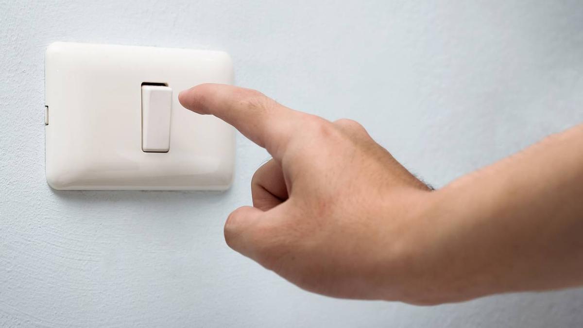 Una persona apaga el interruptor de la luz.