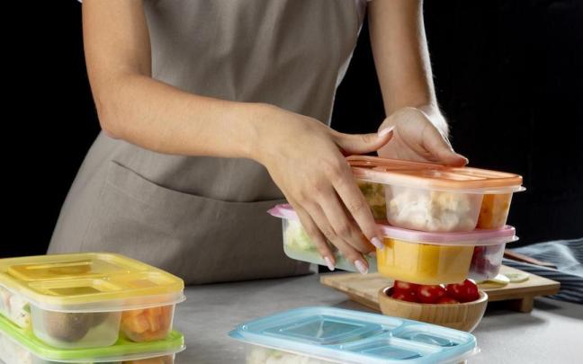 Una mujer prepara varios envases de alimentos.