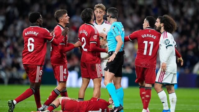 Los jugadores del Sevilla protestan con Peque sobre el terreno de juego.
