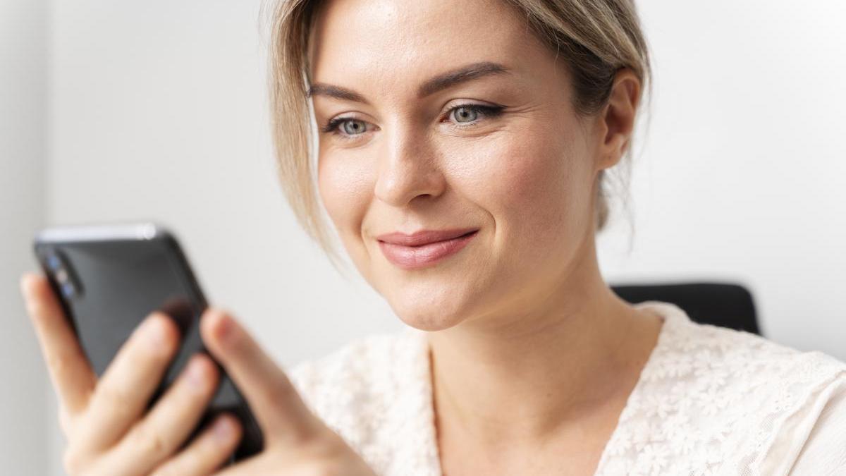 Mujer mira la pantalla del móvil.