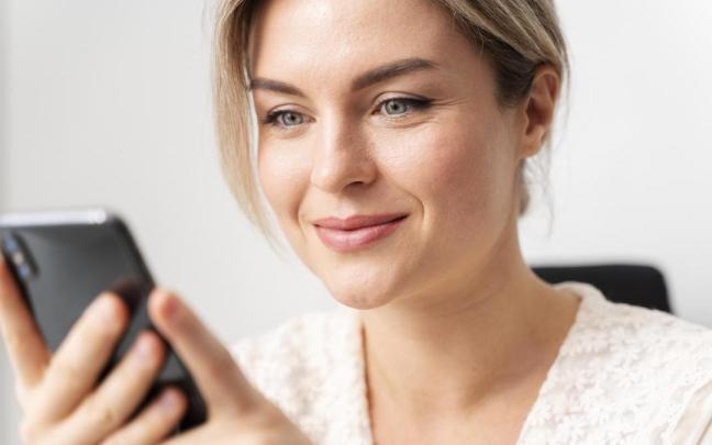 Mujer mira la pantalla del móvil.