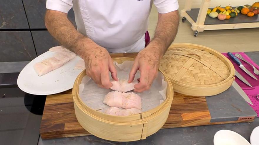 Salpimienta la merluza y coloca los trozos sobre el papel de horno en la superficie de la vaporera.