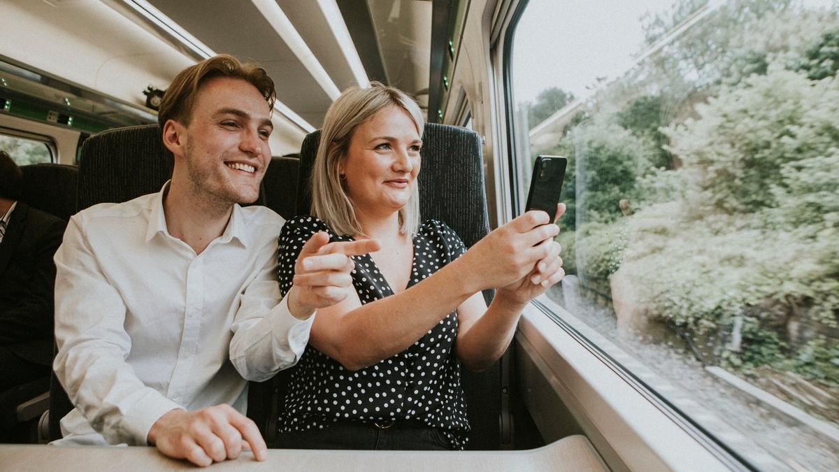 Una pareja utiliza el móvil para hacerse un selfie en el tren.