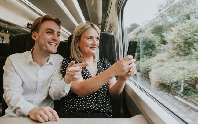 Una pareja utiliza el móvil para hacerse un selfie en el tren.