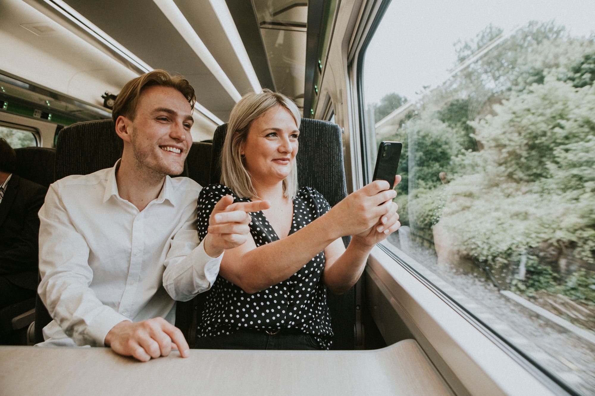 Una pareja utiliza el móvil para hacerse un selfie en el tren.