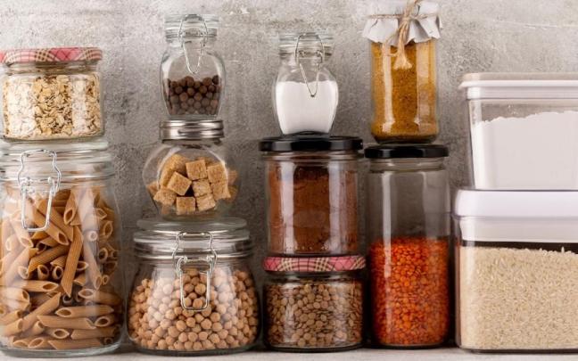 Tarros, botes y tuppers comparten espacio en un estante.