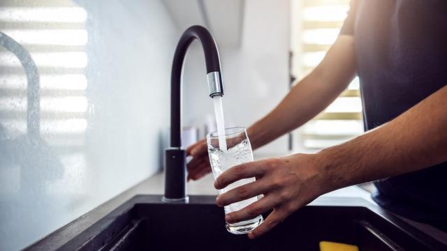 Una persona se sirve un vaso de agua del grifo de su cocina. Una persona se sirve un vaso de agua del grifo de su cocina.