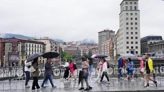Gente paseando por Bilbao en un día de lluvia