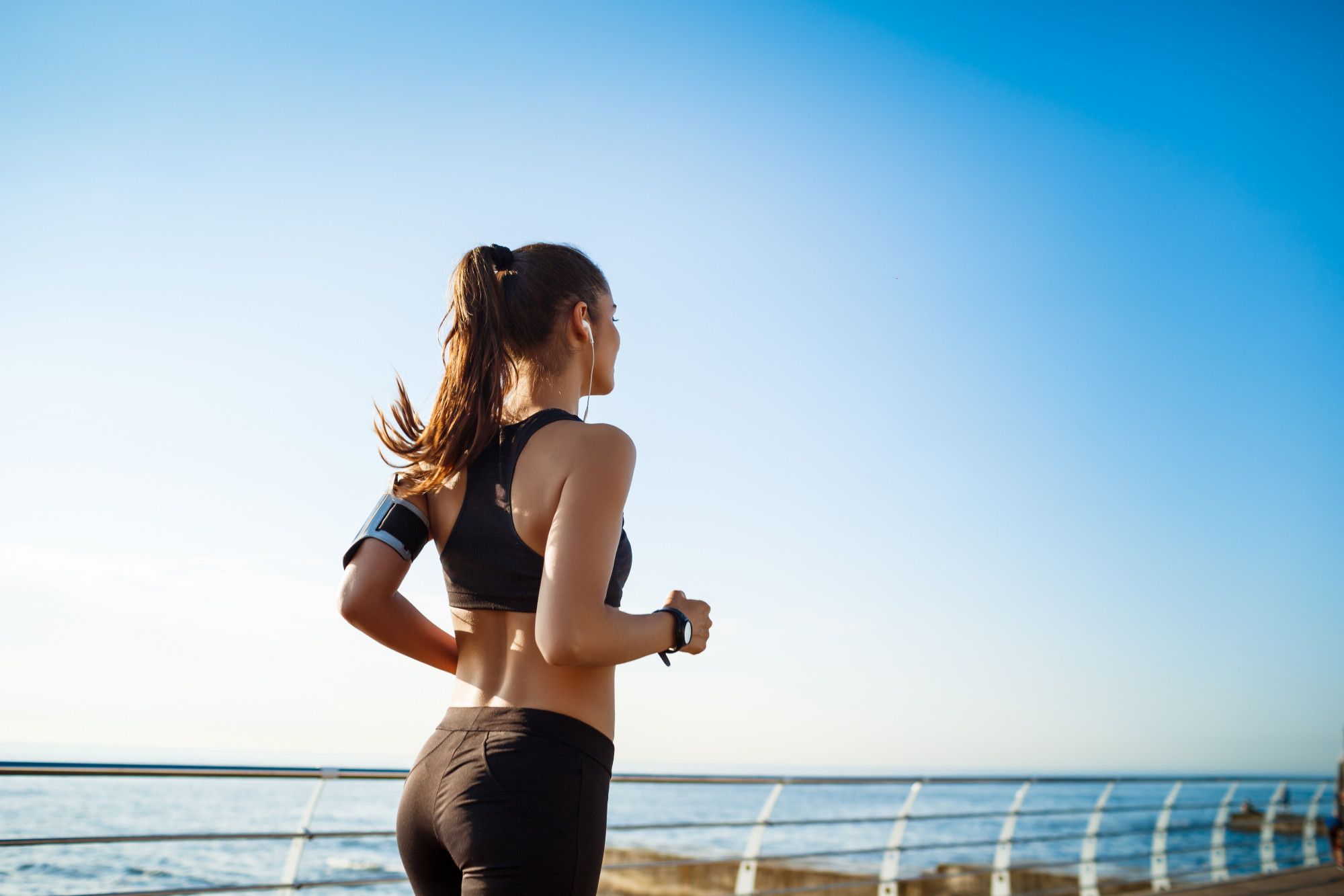Una mujer practica running junto a la orilla del mar.