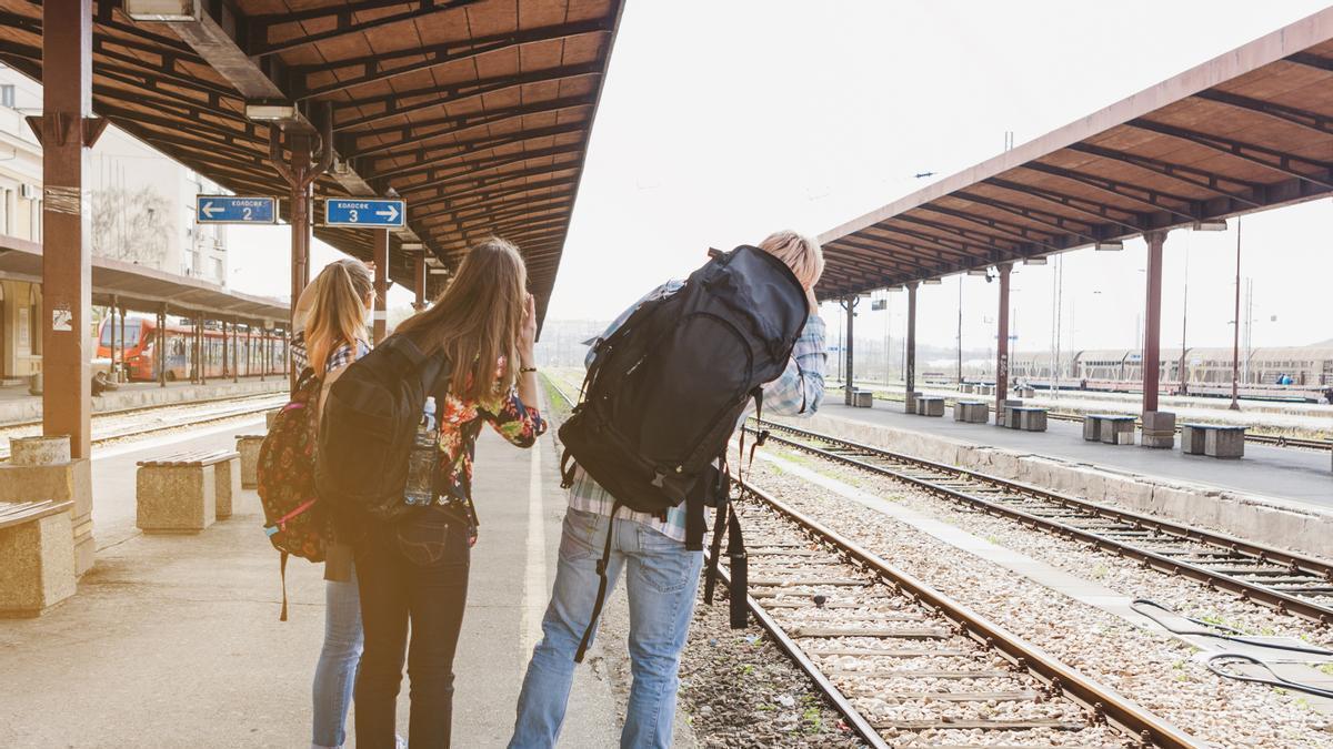 Tres amigos esperan a un tren en una estación.