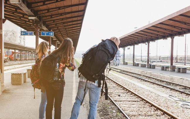 Tres amigos esperan a un tren en una estación.