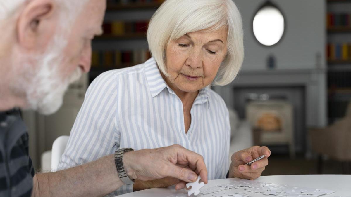Pareja de personas mayores hacen un puzzle.