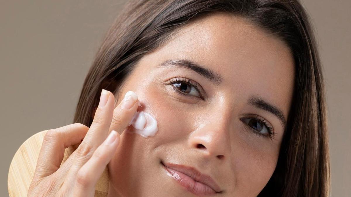 Una mujer se aplica crema hidratante en el rostro.