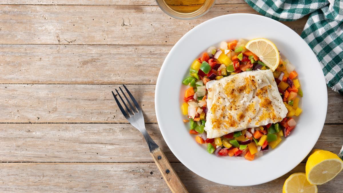 Un plato de pescado con guarnición de verduras.