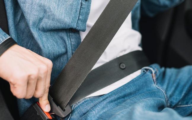 Una persona se coloca el cinturón de seguridad en su coche. Una persona se coloca el cinturón de seguridad en su coche.