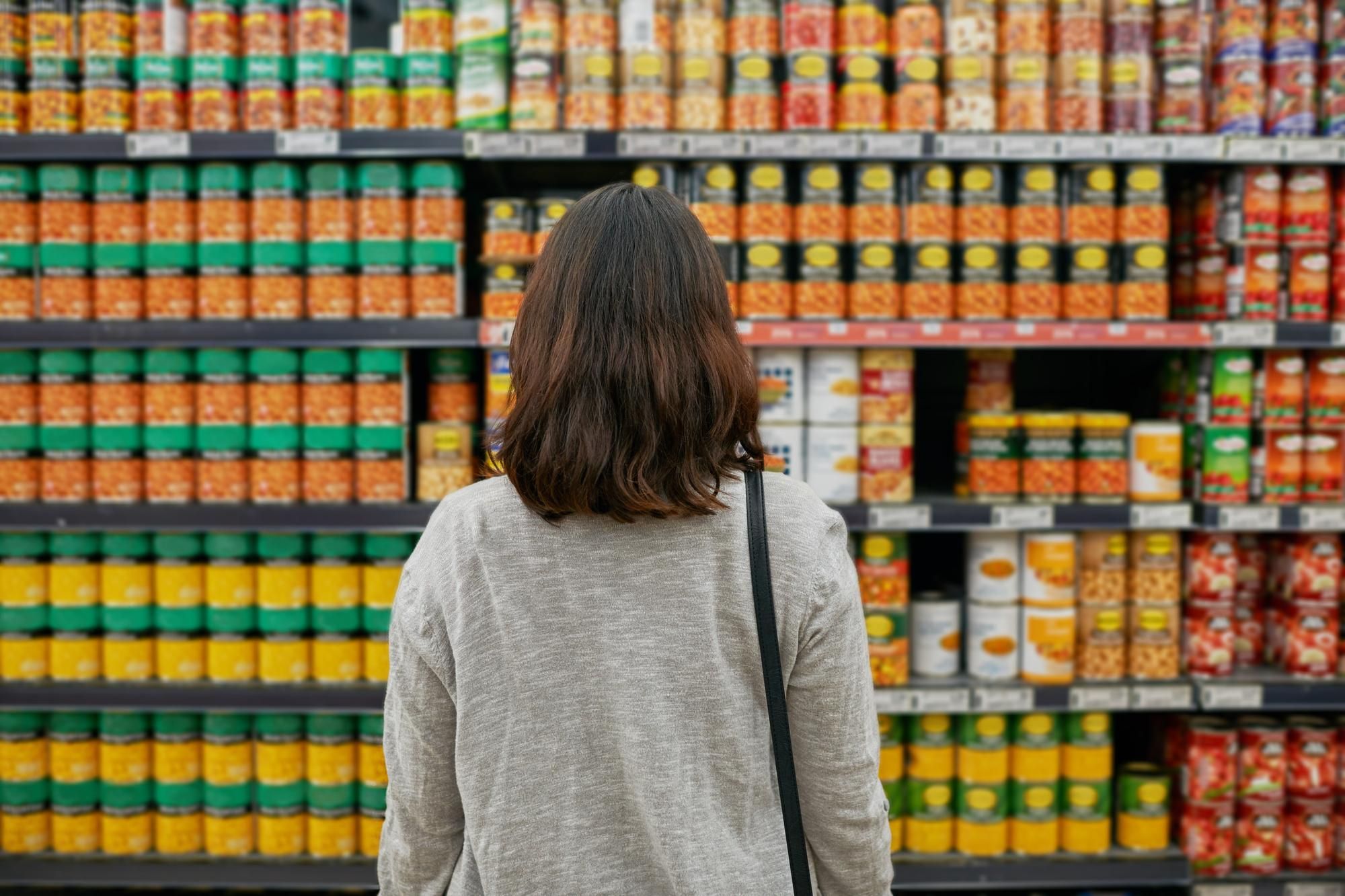 Una mujer frente a la zona de latas de conservas del súper.