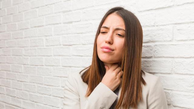 Una mujer se lleva la mano a la garganta.