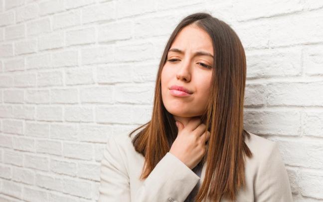 Una mujer se lleva la mano a la garganta.