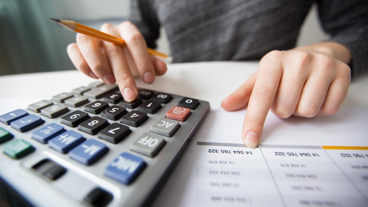 Una persona revisa calculadora en mano las cifras de su nómina.