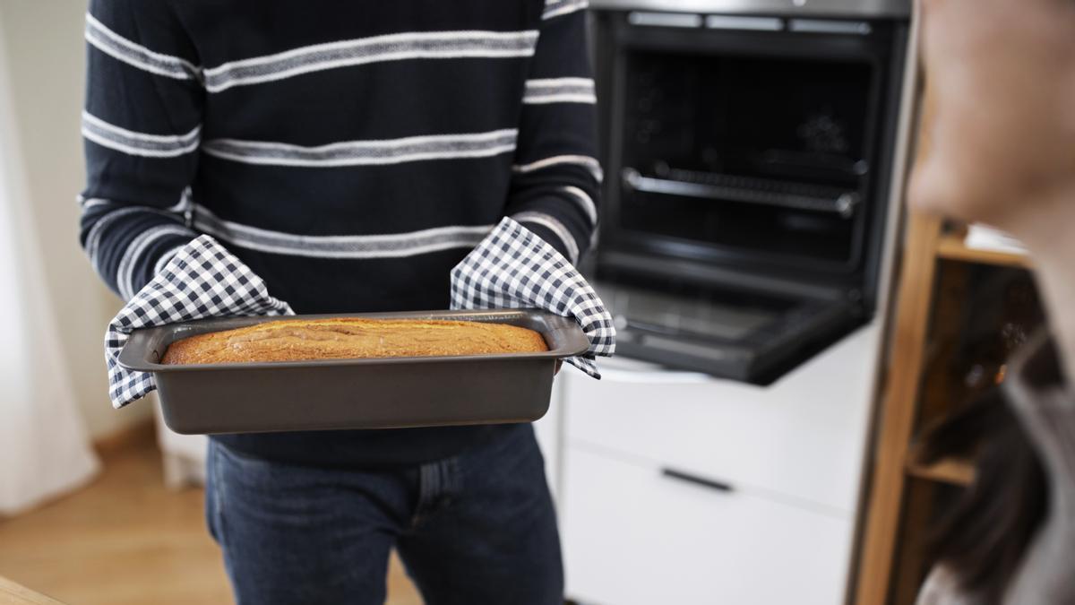 Hombre saca un pastel recién hecho del horno.