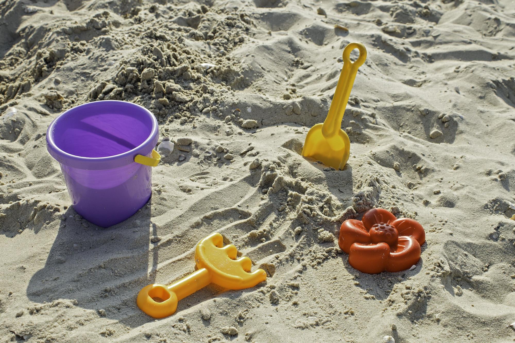 Cubo y juguetes de niños en la playa.