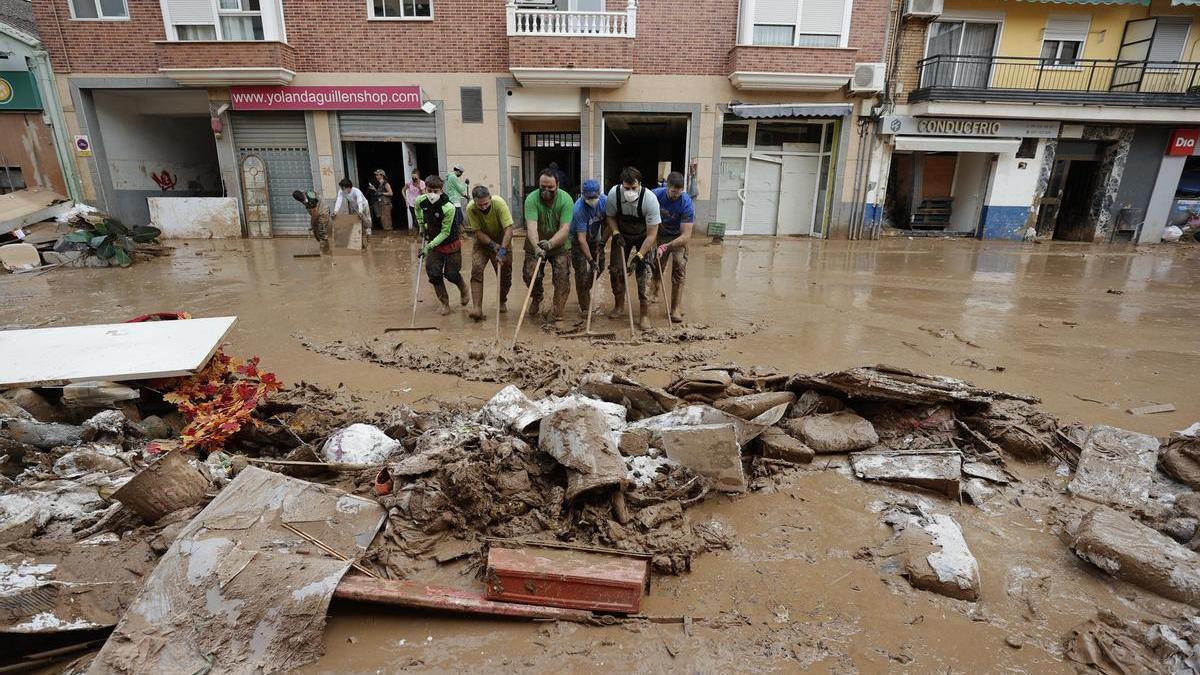 Vecinos de Paiporta limpian el lodo de una calle.