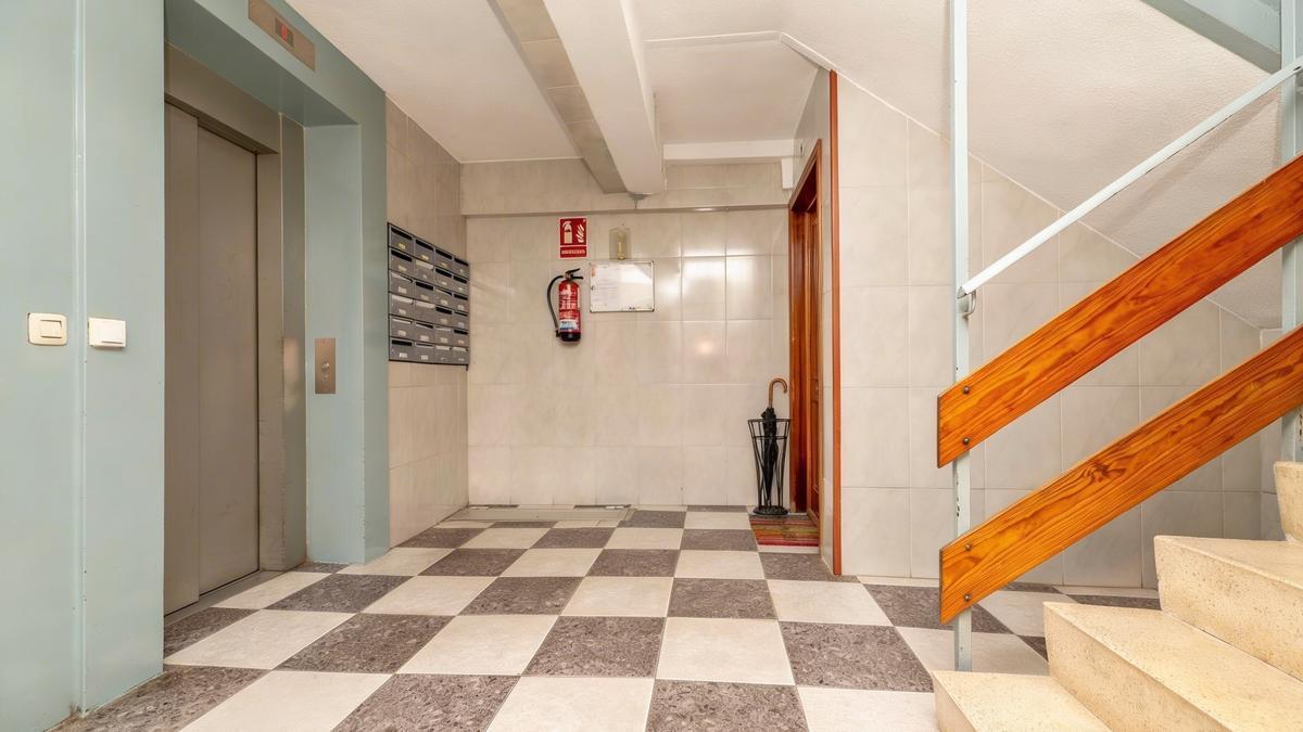 Un paragüero con un paraguas colocado junto a la puerta de una vivienda.