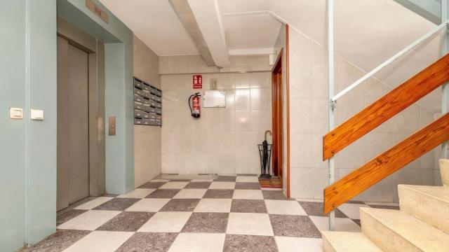 Un paragüero con un paraguas colocado junto a la puerta de una vivienda.