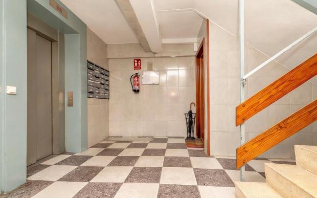 Un paragüero con un paraguas colocado junto a la puerta de una vivienda.