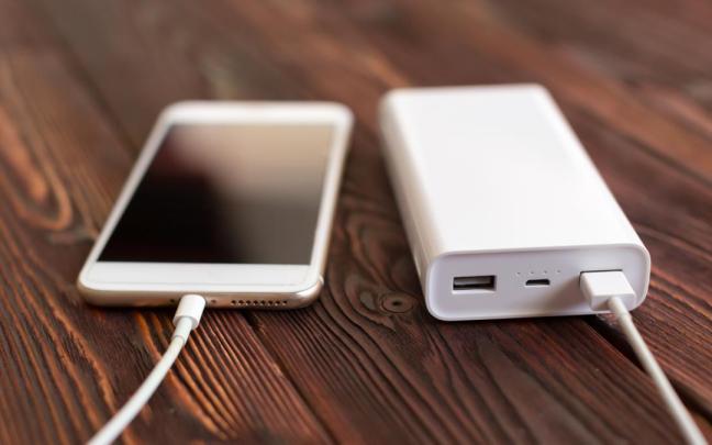 Una persona carga su teléfono con una batería portátil.