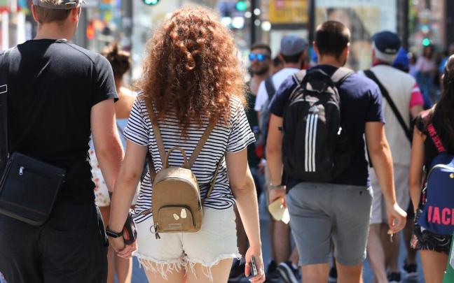 Una pareja cruza de la mano un paso de peatones.