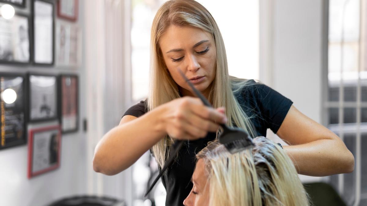 Una peluquera tiñe el pelo a una clienta.