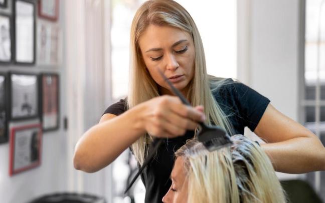 Una peluquera tiñe el pelo a una clienta. Una peluquera tiñe el pelo a una clienta.