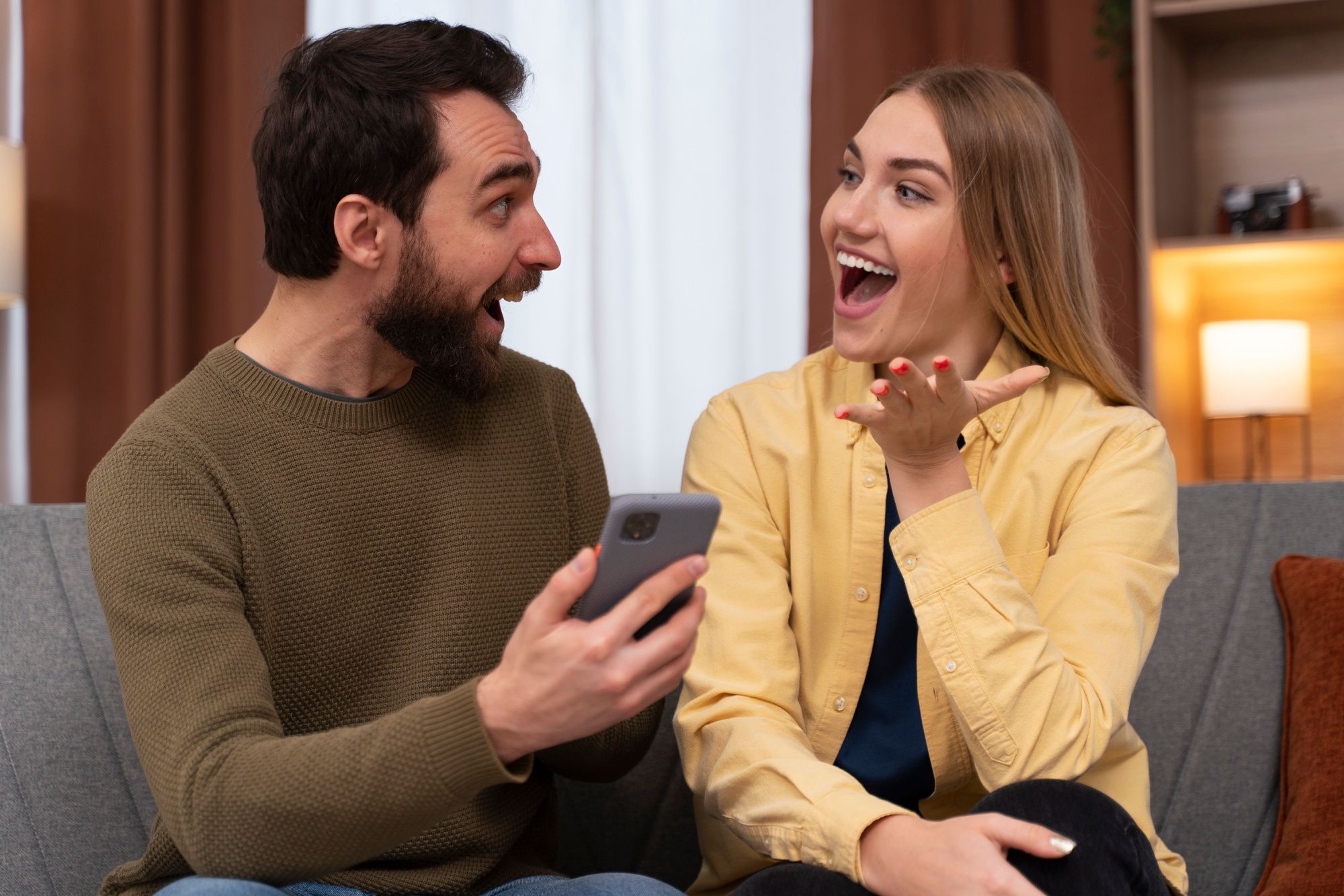 Una pareja refleja alegría en sus rostros tras consultar el móvil.