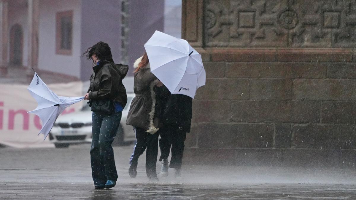 Varias personas intentan sujetar sus paraguas durante una borrasca.