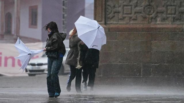Varias personas intentan sujetar sus paraguas durante una borrasca.