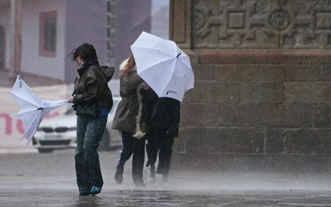 Varias personas intentan sujetar sus paraguas durante una borrasca.