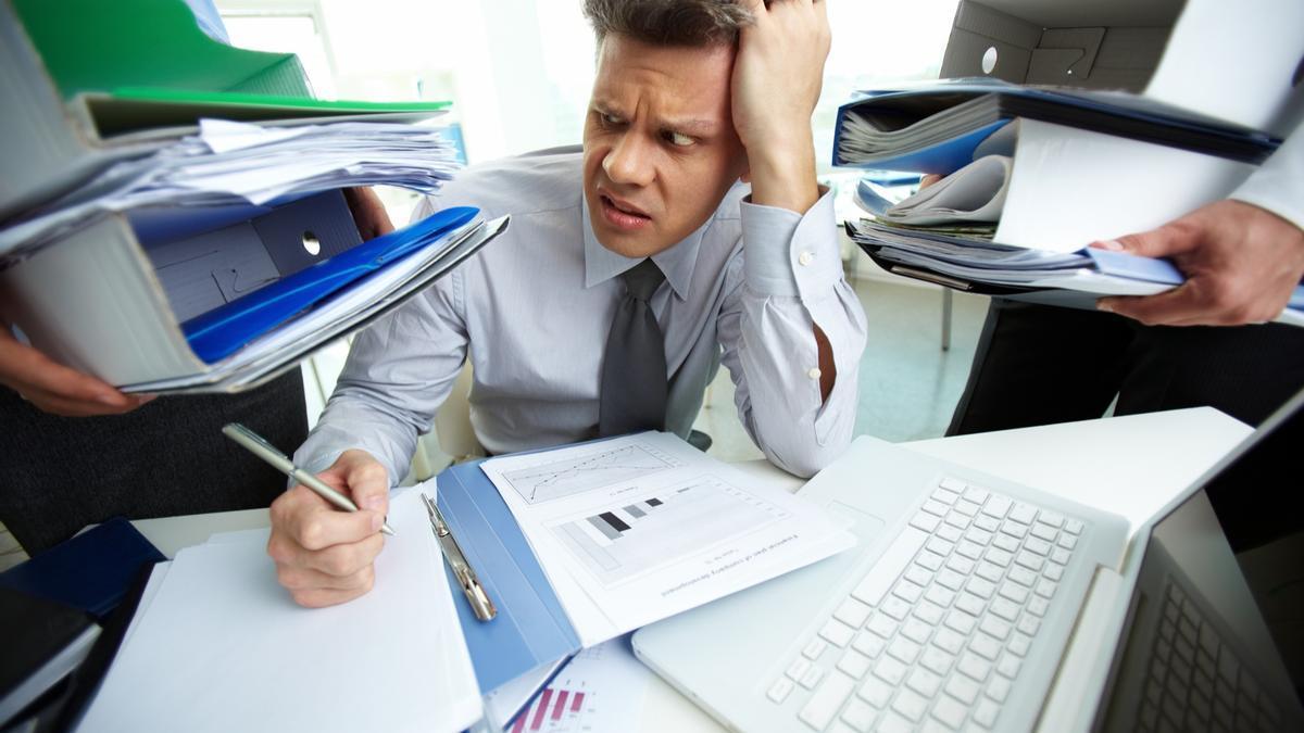 Un hombre desbordado por su obligaciones en el trabajo.