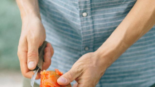 Un cocinero pelando tomates en la cocina.
