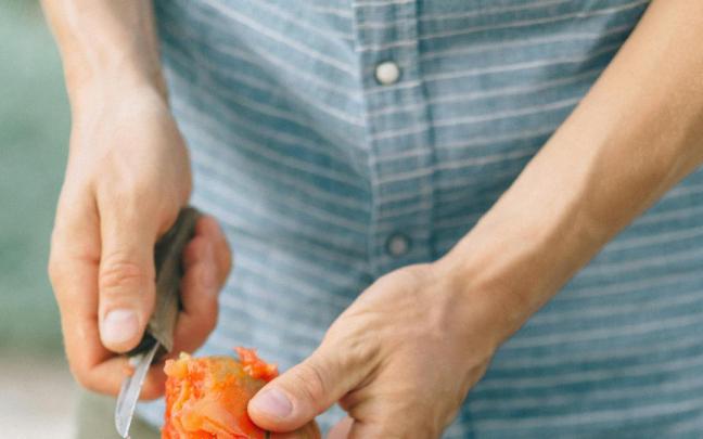 Un cocinero pelando tomates en la cocina.