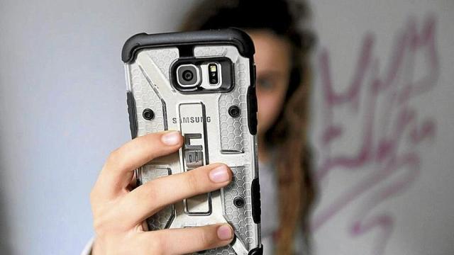 Una menor utiliza un teléfono móvil.