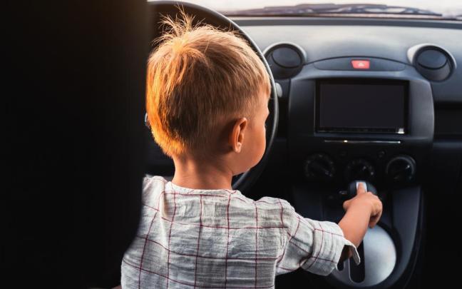 Un niño ajeno a esta historia juega dentro de un coche. / Cute little boy playing in car and acting like real adult driver. Un niño ajeno a esta historia juega dentro de un coche.