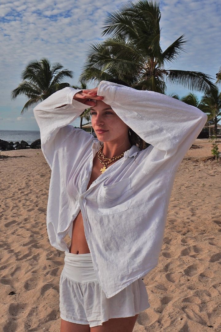 Una chica en la playa con una camisa oversize.