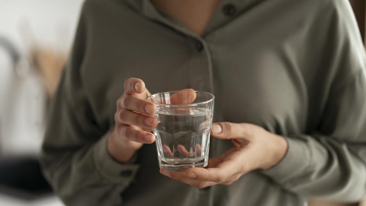 Manos de una mujer sostienen un vaso de agua