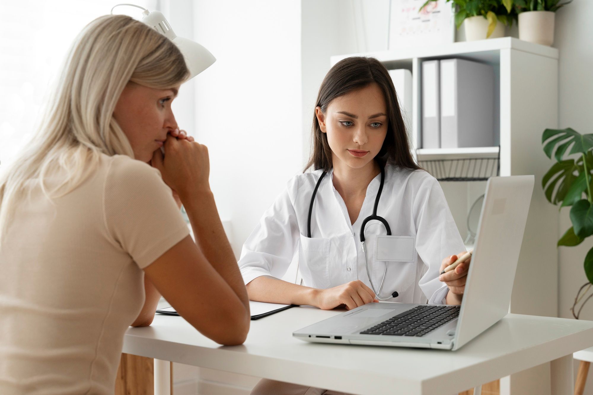 Una médica muestra en su ordenador un informe a una paciente.
