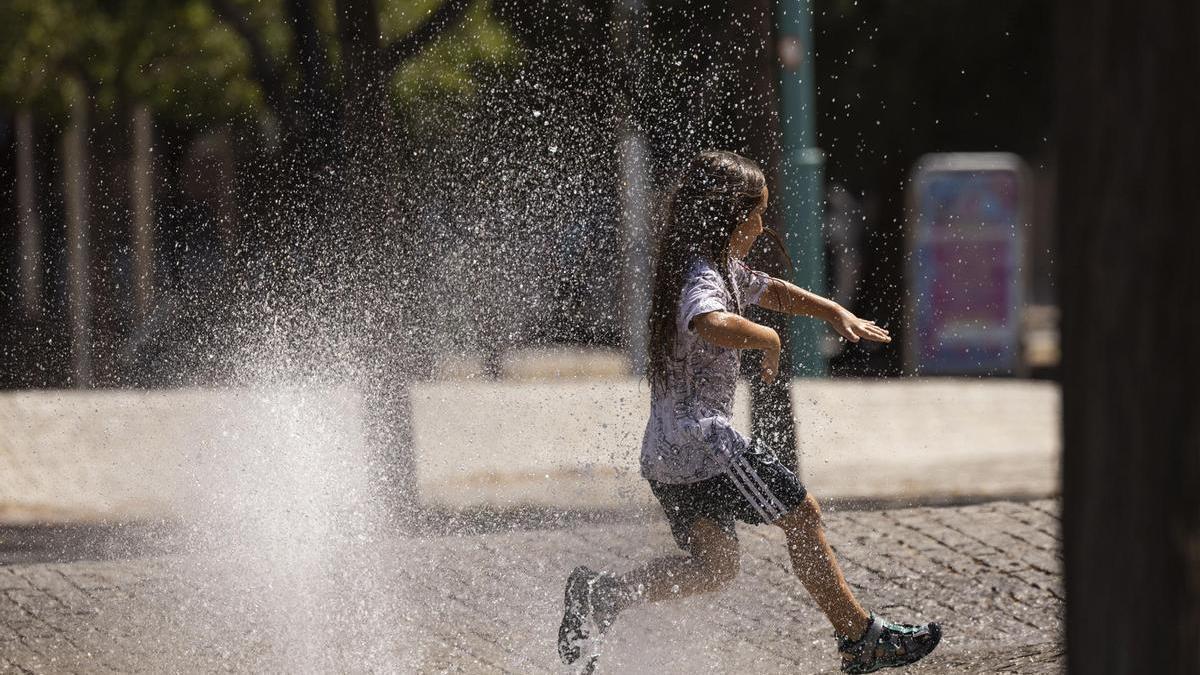 Una niña juega en una fuente en plena ola de calor.