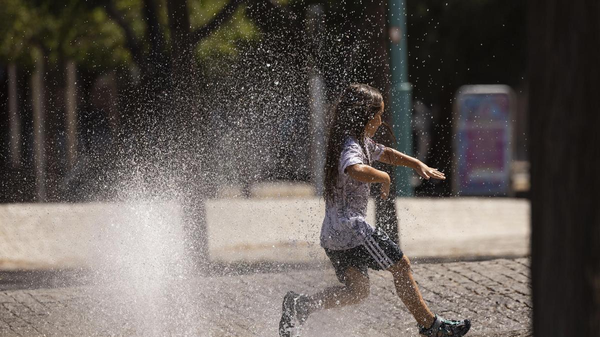 Una niña juega en una fuente en plena ola de calor.